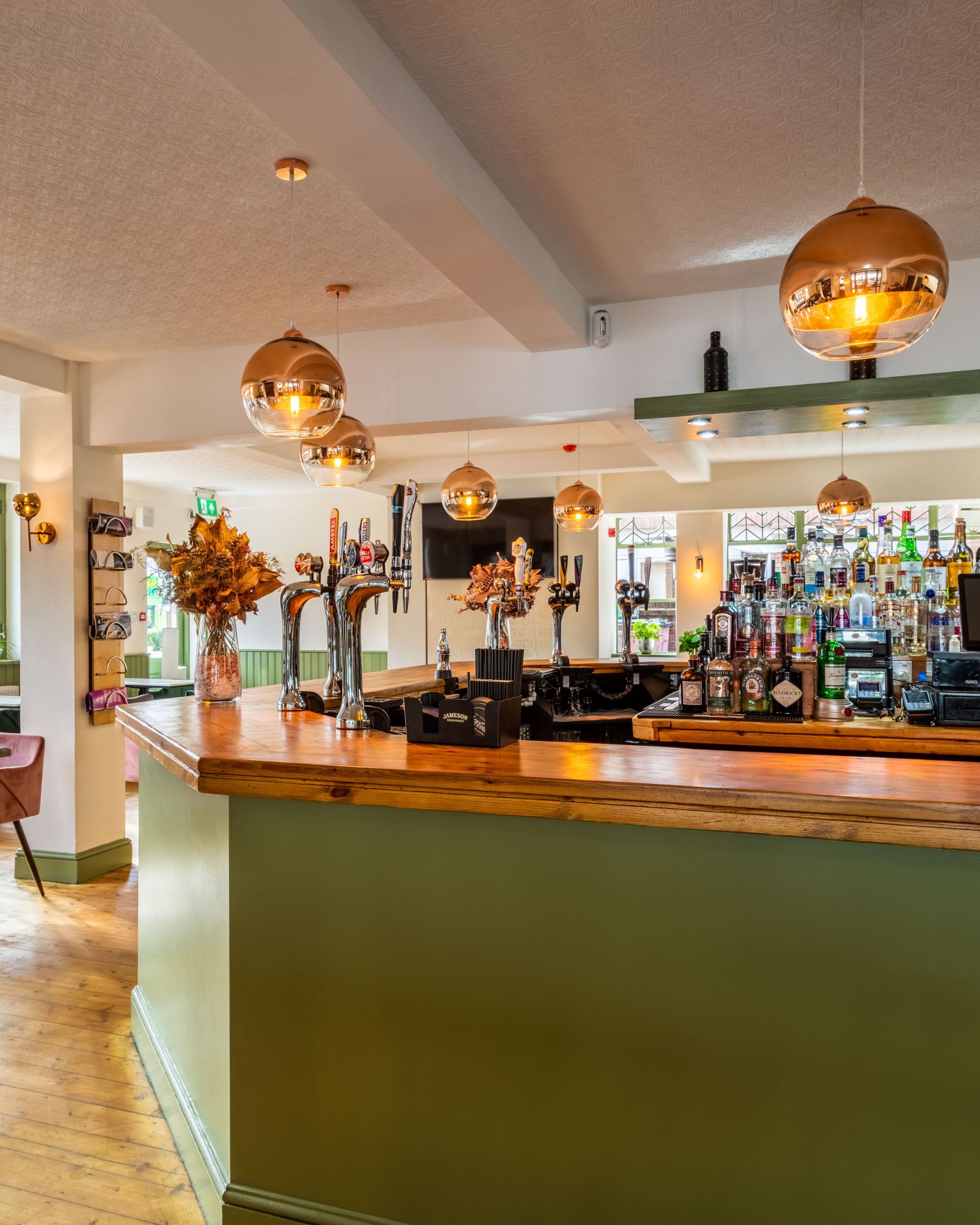 The bar of a traditional English pub with copper pendant lights and taps ready to pour.